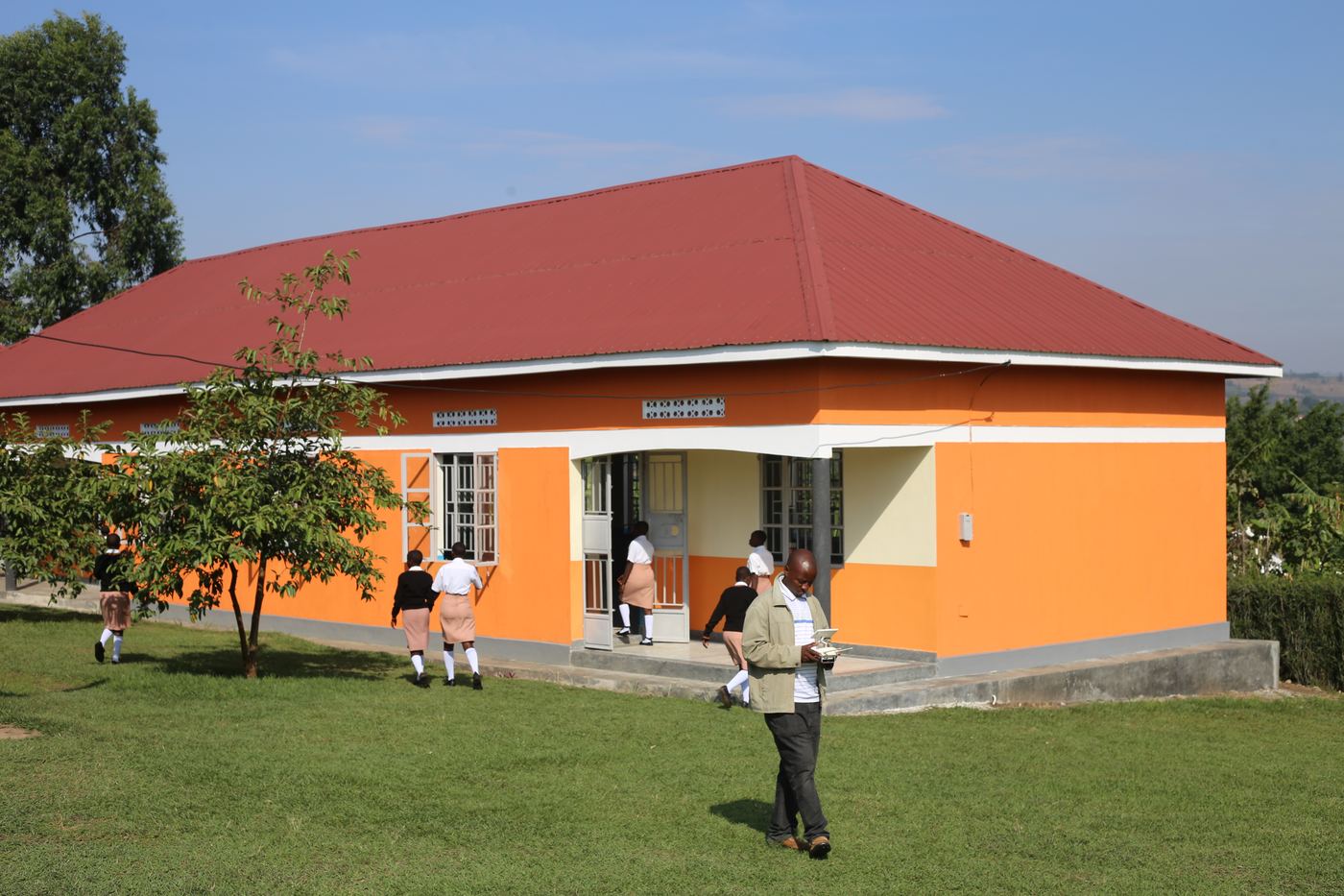 Students walking past an orange classroom block on the Eximius campus